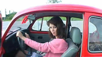 Bimba siting barefoot in her volkswagen car revving the engine