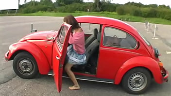 Bimba siting barefoot in her volkswagen car revving the engine