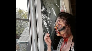 Smoking woman with makeup by the window