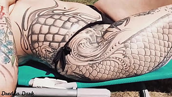 Tattooed horny brunette with big boobs sunbathing in the yard and rubbing sunscreen on her tits