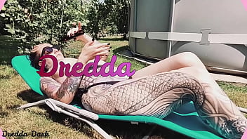 Tattooed horny brunette with big boobs sunbathing in the yard and rubbing sunscreen on her tits