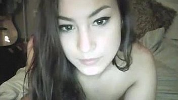 Pierced navel chick fucks herself on bed