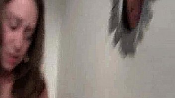 Brunette sucking two cocks at gloryhole