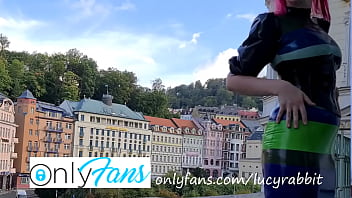 Latex tight fitting striped dress publicly on the balcony