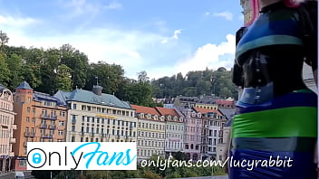 Latex tight fitting striped dress publicly on the balcony