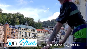 Latex tight fitting striped dress publicly on the balcony