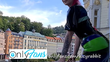 Latex tight fitting striped dress publicly on the balcony