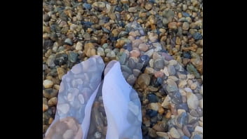 Playing with my feet in white socks with pebbles on the beach Playing with my feet in white socks with pebbles on the beach
