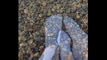 Playing with my feet in white socks with pebbles on the beach Playing with my feet in white socks with pebbles on the beach
