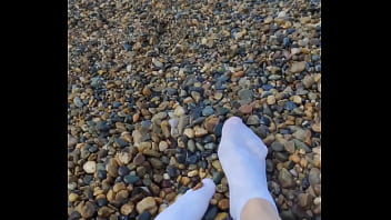 Playing with my feet in white socks with pebbles on the beach