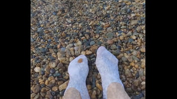 Playing with my feet in white socks with pebbles on the beach