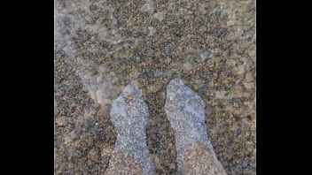 Playing with my feet in white socks with pebbles on the beach