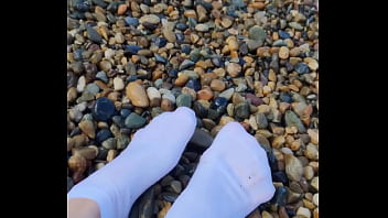 Playing with my feet in white socks with pebbles on the beach Playing with my feet in white socks with pebbles on the beach