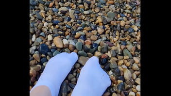 Playing with my feet in white socks with pebbles on the beach