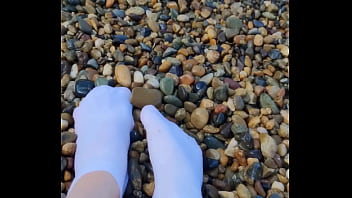 Playing with my feet in white socks with pebbles on the beach